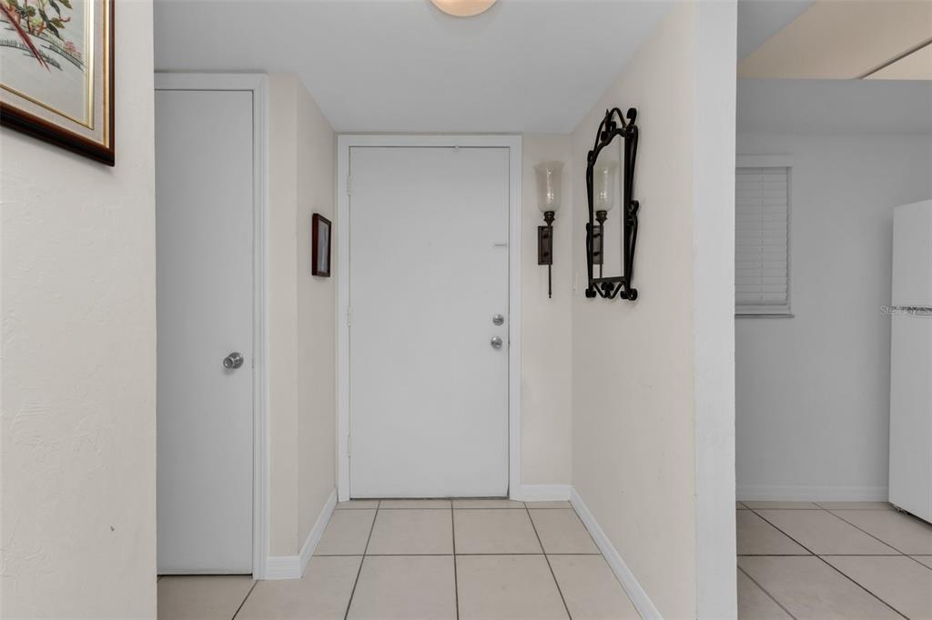 An entryway features a white front door, tiled flooring, and wall-mounted light fixtures — 3100 HARBOR BOULEVARD UNIT 203, PORT CHARLOTTE, FL