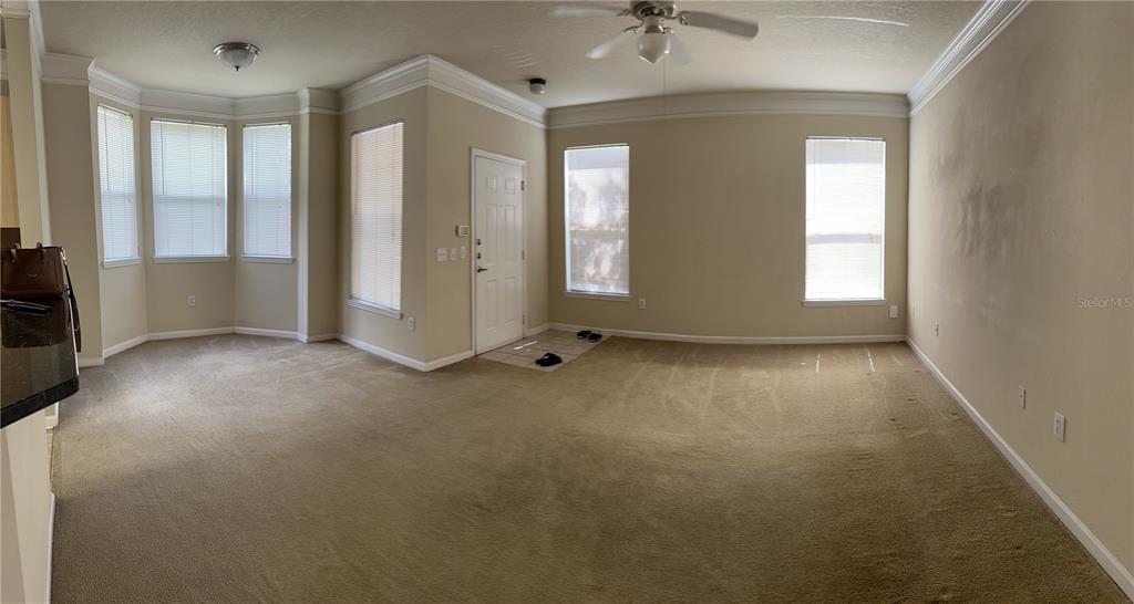 A carpeted living room features a bay window, a ceiling fan, and an entryway door — 8855 VILLA VIEW CIRCLE UNIT 105, ORLANDO, FL
