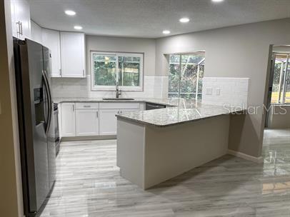 A kitchen with white cabinets, granite countertops, stainless steel appliances, and light-colored tile flooring — 2 SUNSET BAY DRIVE, BELLEAIR, FL