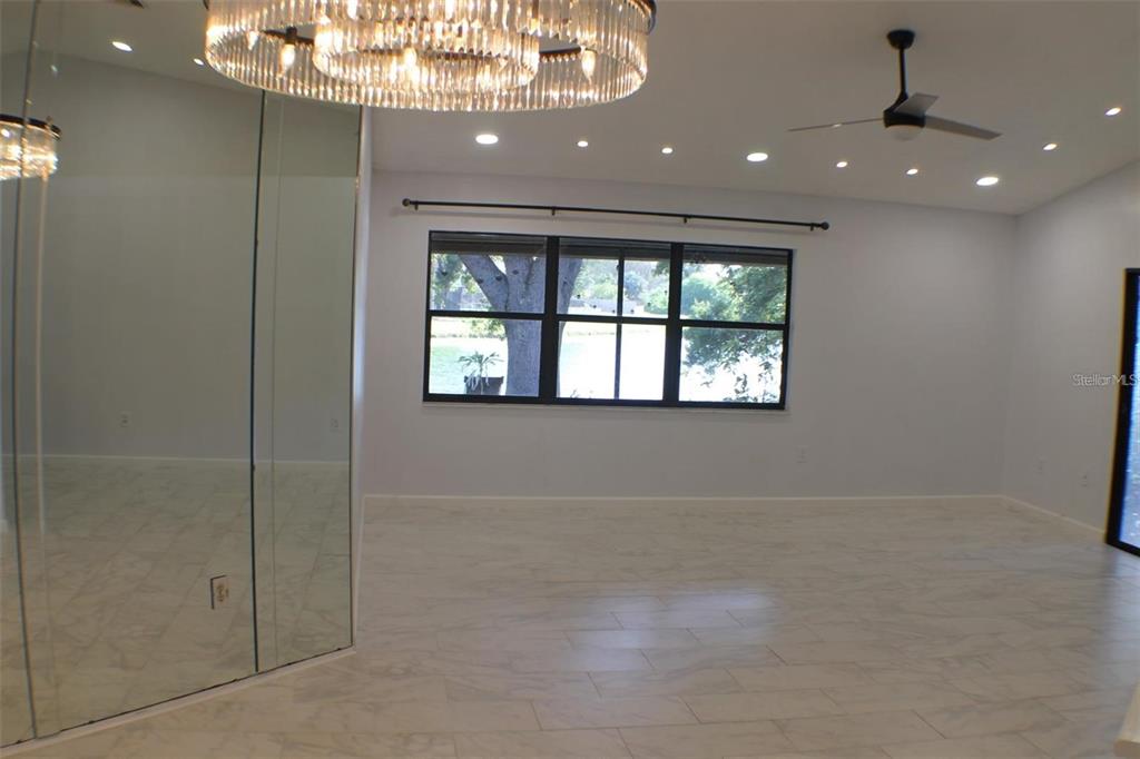 A bright room with light tile floors, a large crystal chandelier, and a mirrored wall — 1723 BELL RANCH STREET, BRANDON, FL