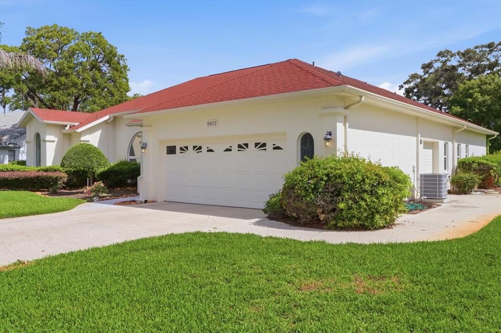 A single-story house with a red roof, white stucco exterior, and a two-car garage — 9401 MERRIWEATHER DRIVE, WEEKI WACHEE, FL