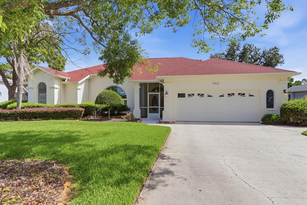A single-story house with a red roof, white stucco exterior, and a two-car garage — 9401 MERRIWEATHER DRIVE, WEEKI WACHEE, FL
