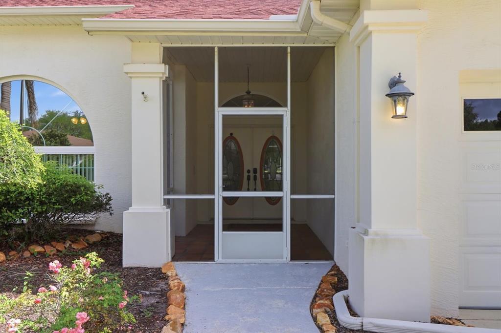 A screened-in front entryway with a tiled floor leads to double front doors — 9401 MERRIWEATHER DRIVE, WEEKI WACHEE, FL