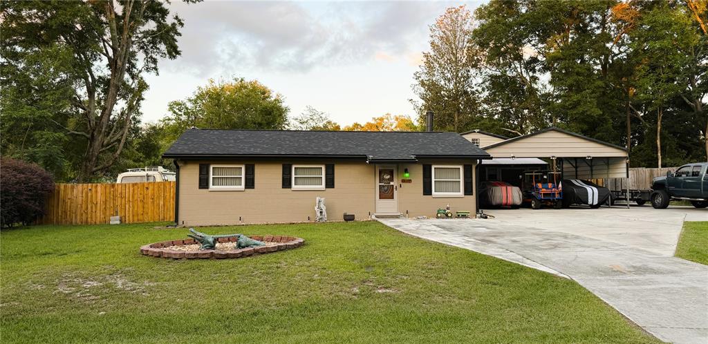A single-story tan brick house with a dark roof, shutters, and an attached carport — 18143 NW 251ST TERRACE, HIGH SPRINGS, FL