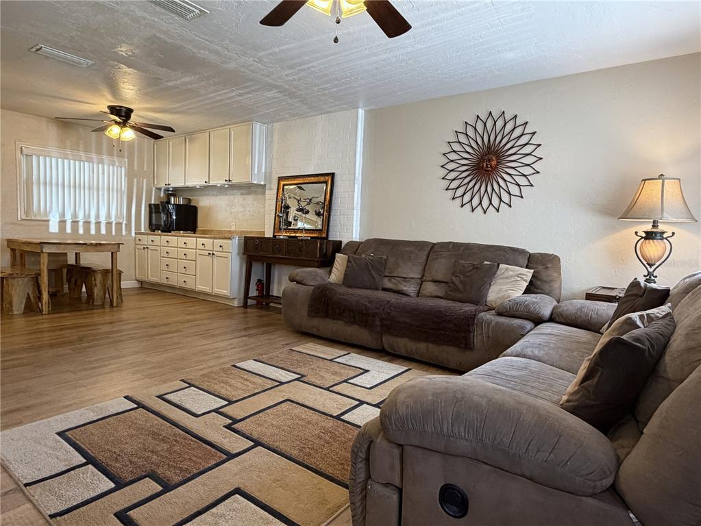 A living room with a brown sectional sofa, area rug, dining table, and kitchen cabinets — 18143 NW 251ST TERRACE, HIGH SPRINGS, FL