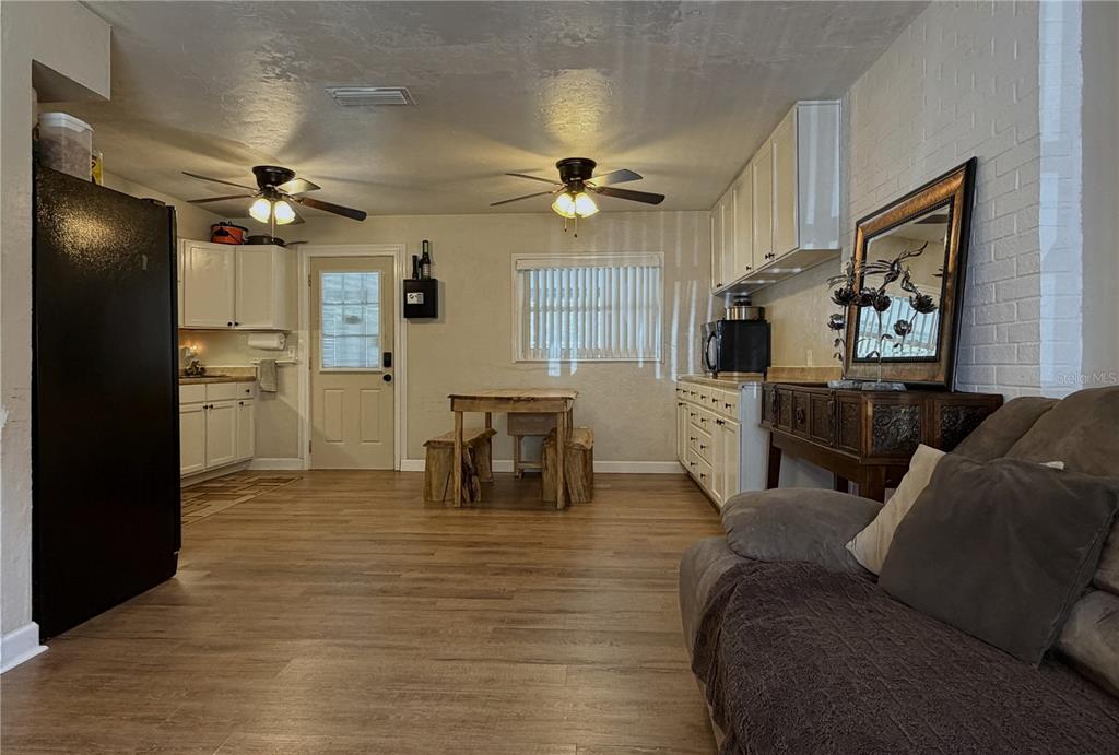 A kitchen and dining area features white cabinets, wood-look flooring, and two ceiling fans — 18143 NW 251ST TERRACE, HIGH SPRINGS, FL