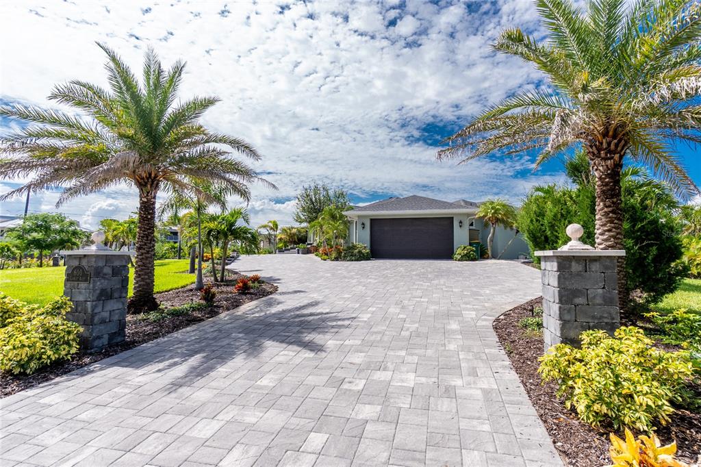 A paved driveway leads to a garage, framed by two stone pillars and palm trees — 600 LOOKOUT ALLEY, PLACIDA, FL