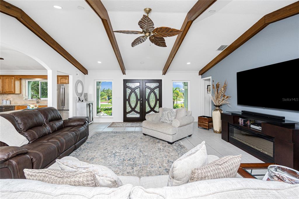 A living room features vaulted ceilings with exposed beams, a ceiling fan, and tile flooring — 600 LOOKOUT ALLEY, PLACIDA, FL