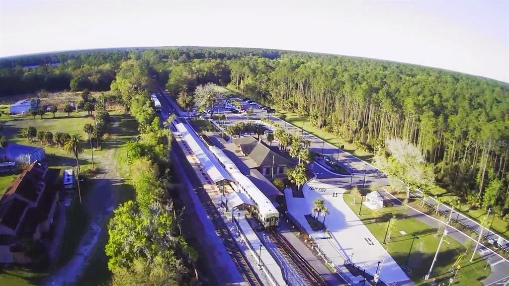 An aerial view shows a train at a station surrounded by a parking lot and forest — 2504 OLD NEW YORK AVENUE, DELAND, FL