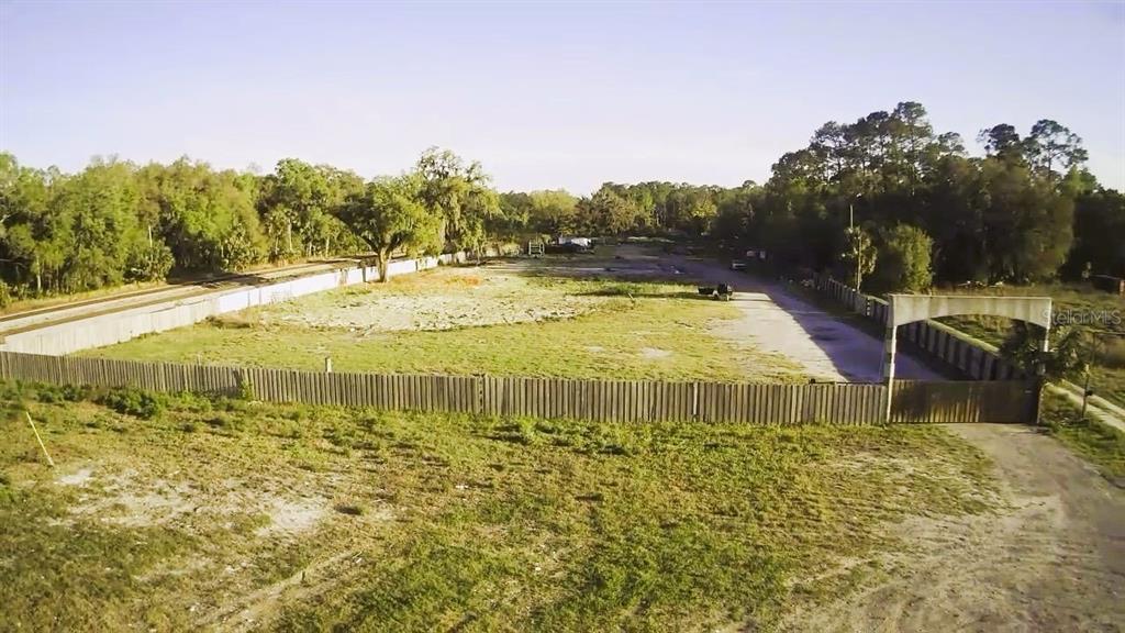 An aerial view of a large, fenced, vacant lot with trees in the background — 2504 OLD NEW YORK AVENUE, DELAND, FL