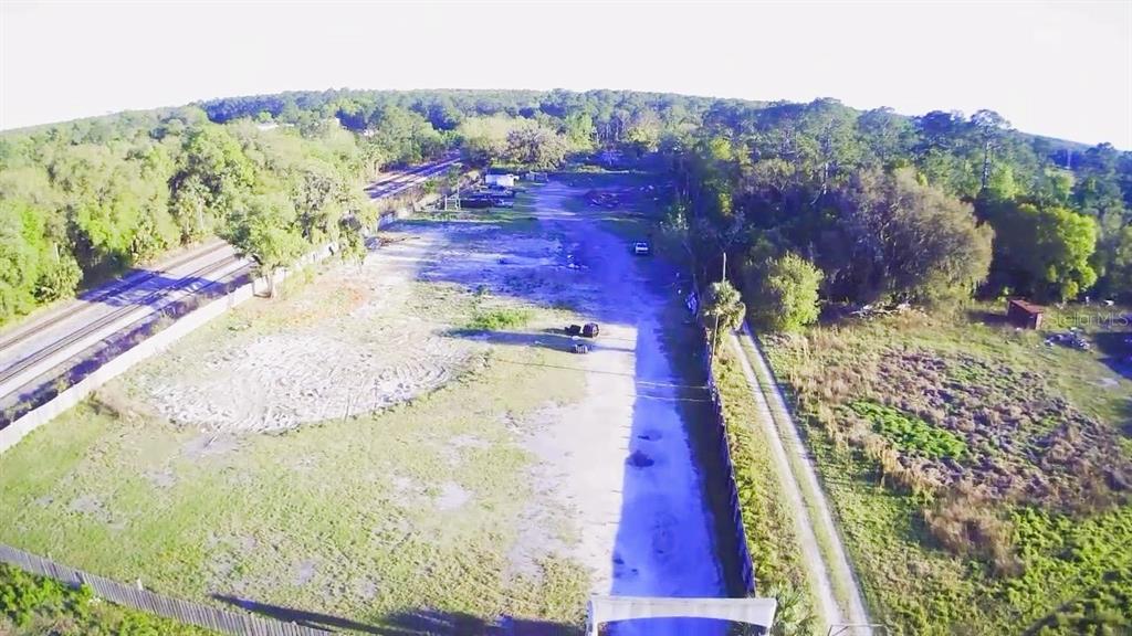 An aerial view shows a long, narrow, partially cleared lot bordered by trees and tracks — 2504 OLD NEW YORK AVENUE, DELAND, FL
