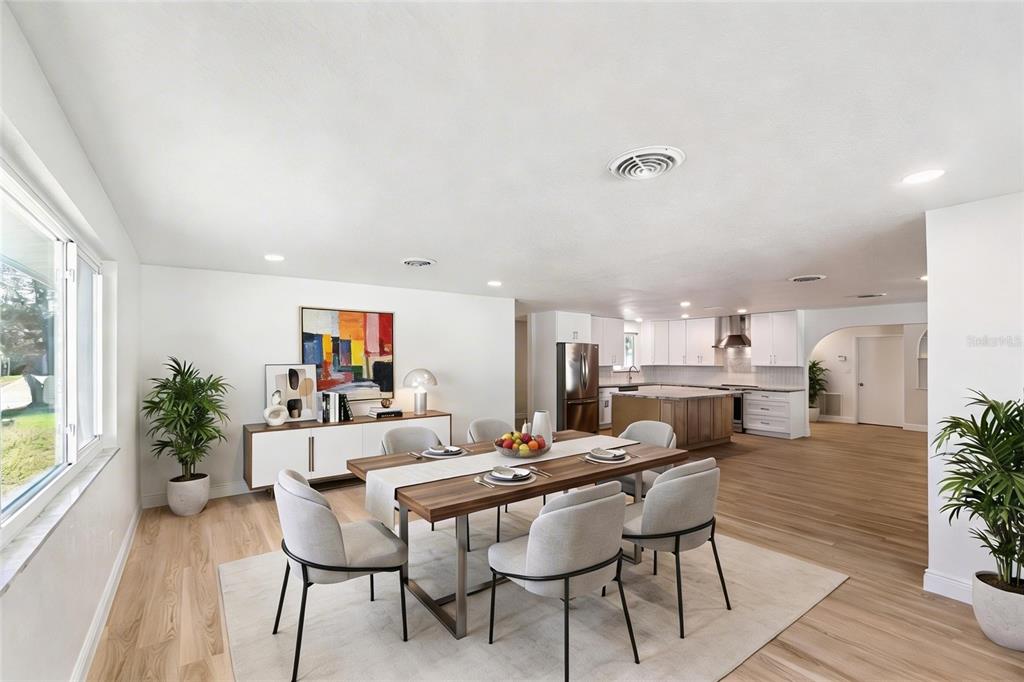 A dining room with a wooden table and chairs sits adjacent to an open kitchen — 3050 PRINCETON AVENUE, DAYTONA BEACH, FL
