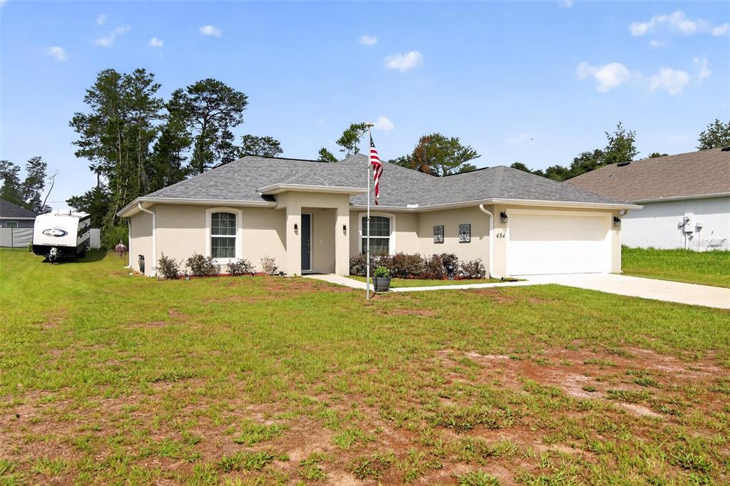 A single-story house with a beige exterior, a gray shingled roof, and a two-car garage — 484 MARION OAKS LANE, OCALA, FL