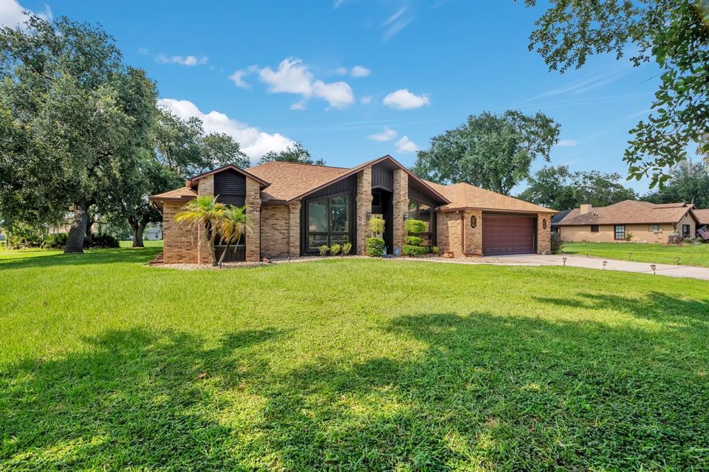 A single-story brick house with a brown shingled roof and a two-car garage — 3251 PINEWOOD COURT, KISSIMMEE, FL