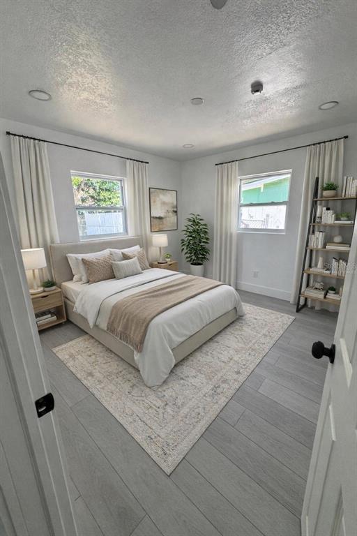 A bedroom features a bed, two windows with curtains, a bookshelf, and light wood flooring — 2148 CATALINA DRIVE N, CLEARWATER, FL