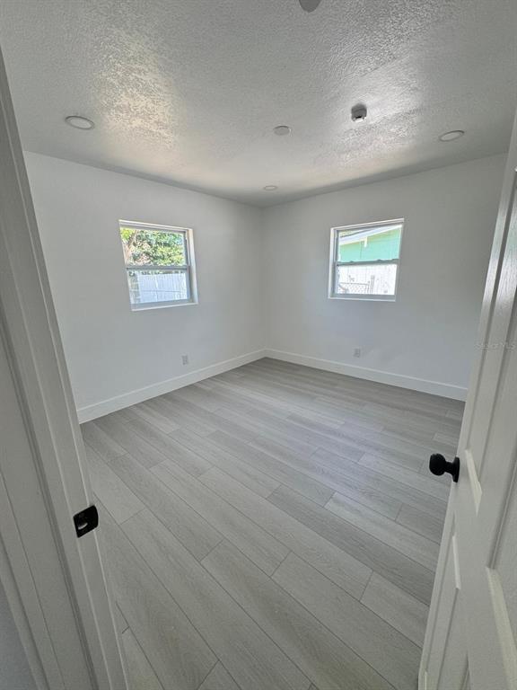 An empty bedroom with white walls, light wood-look flooring, and two windows — 2148 CATALINA DRIVE N, CLEARWATER, FL