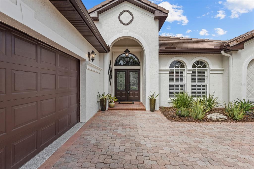 A home office with dark wood floors, built-in cabinetry, two armchairs, and arched windows — 7622 DESERT INN WAY, BRADENTON, FL