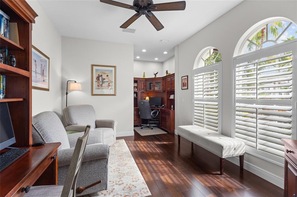 A living room features a stone fireplace, a wall-mounted television, and a view of a patio — 7622 DESERT INN WAY, BRADENTON, FL