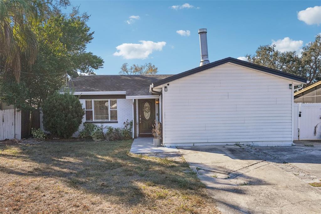 A single-story house with white siding and brick, a front door, and a concrete driveway — 4508 W PEARL AVENUE, TAMPA, FL