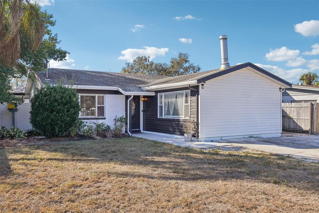A single-story house with white and dark siding, a metal chimney, and a front lawn — 4508 W PEARL AVENUE, TAMPA, FL