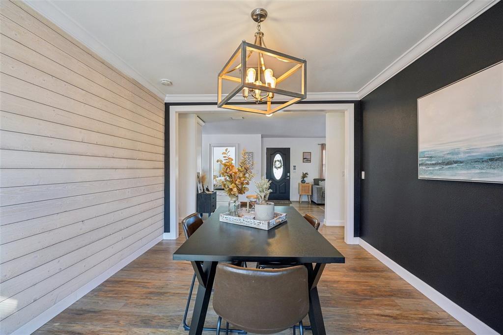 A dining room features a black table, shiplap wall, and a geometric light fixture — 4508 W PEARL AVENUE, TAMPA, FL