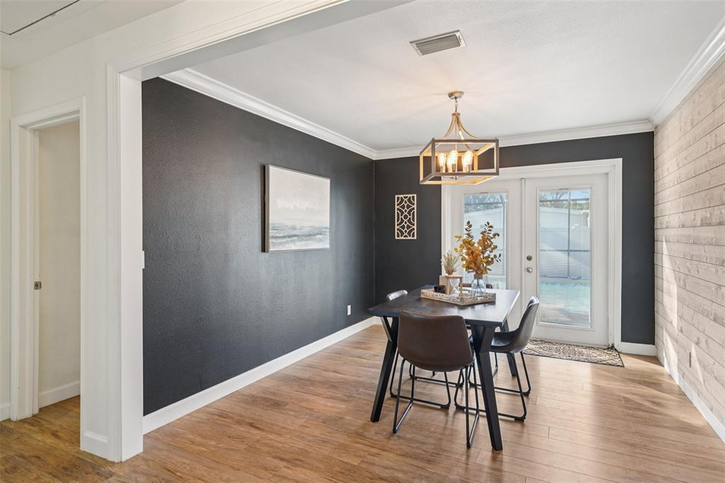 A dining room features a dark accent wall, wood-look flooring, and a modern light fixture — 4508 W PEARL AVENUE, TAMPA, FL