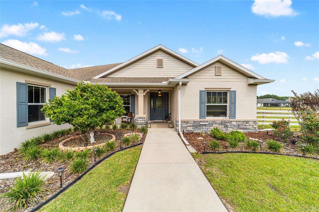 A single-story house with a concrete walkway, stone accents, and blue shutters — 1983 NW 79TH LOOP, OCALA, FL