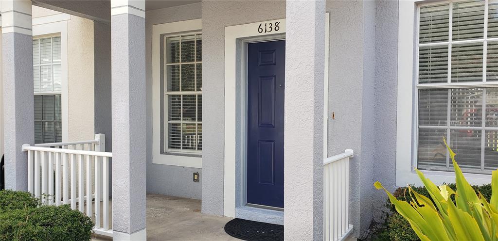A blue front door is centered on a covered porch with white railings and columns — 6138 OLIVEDALE DRIVE, RIVERVIEW, FL