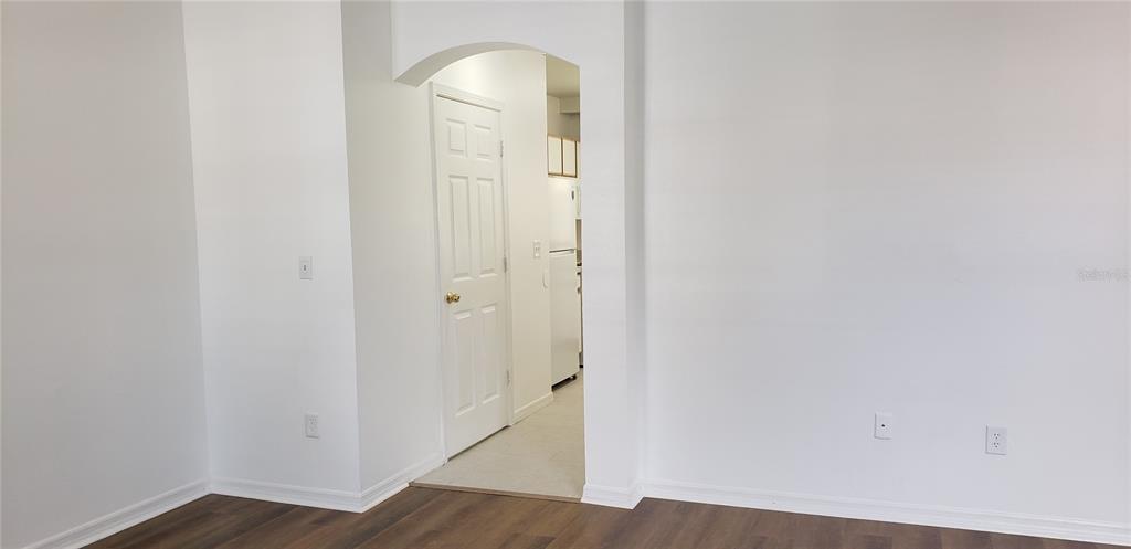 A room with white walls, wood-look flooring, and an arched doorway leading to a kitchen — 6138 OLIVEDALE DRIVE, RIVERVIEW, FL