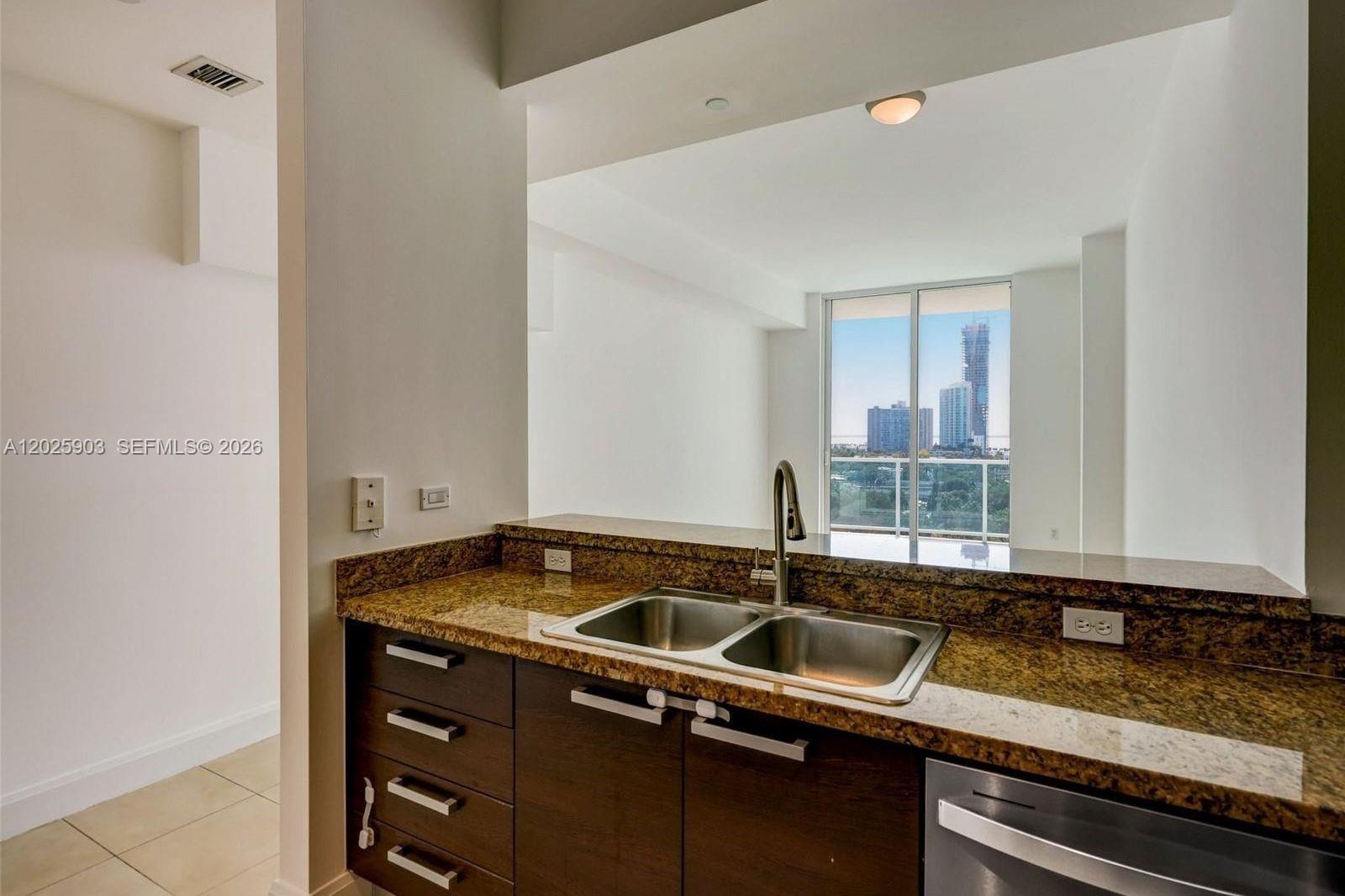 A kitchen sink with granite countertops overlooks a living area with a city view — 2525 SW 3rd Ave # 1009, Miami FL 33129, MIAMI, FL