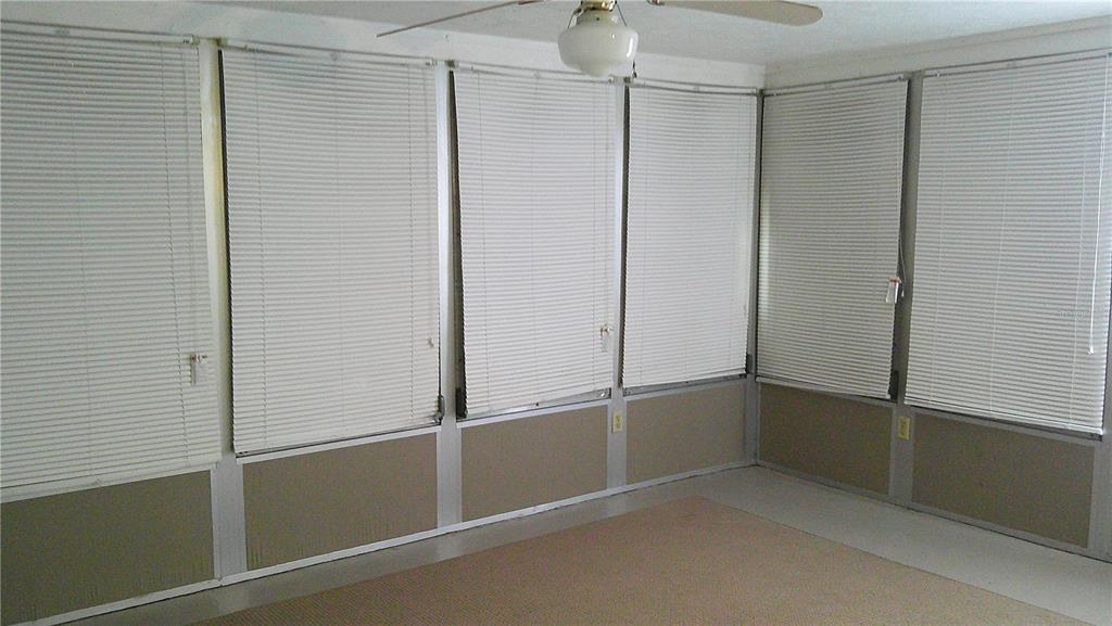 A room with carpeted flooring, a ceiling fan, and multiple windows covered by white blinds — 1203 CHANCELLOR DRIVE, HOLIDAY, FL
