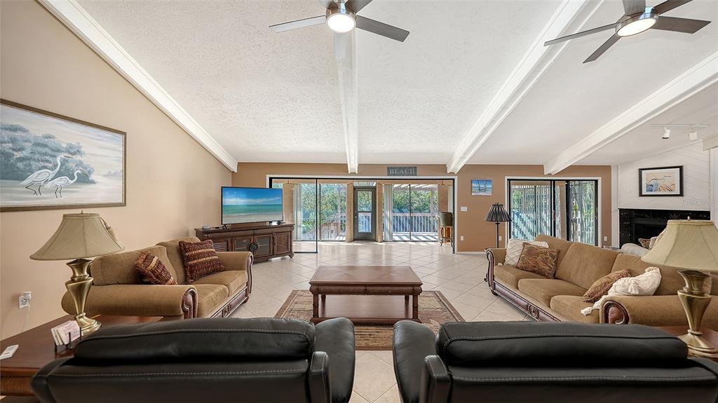 A spacious living room features vaulted ceilings, tile flooring, two sofas, and a sliding glass door — 3131 BAYOU SOUND, LONGBOAT KEY, FL