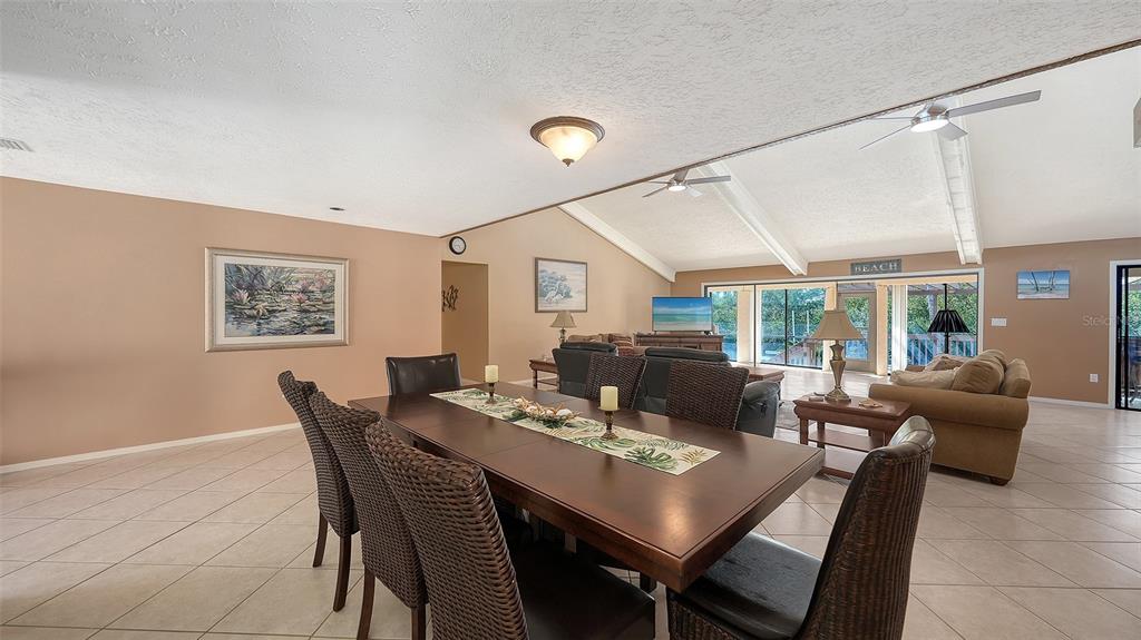 A dining area with a wooden table and wicker chairs opens into a living room — 3131 BAYOU SOUND, LONGBOAT KEY, FL