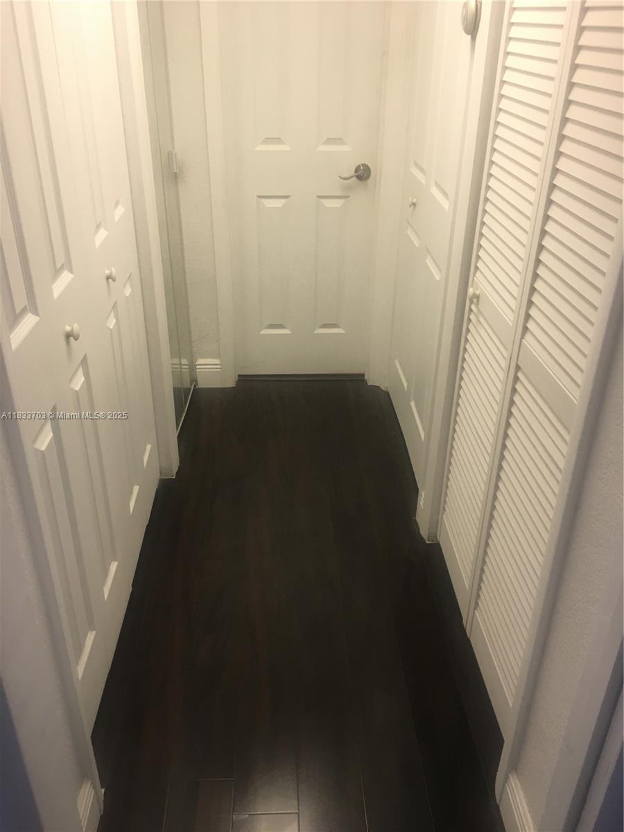 A narrow hallway features dark wood flooring and several white doors with louvered panels — 1750 NE 115th St # 608, Miami FL 33181, MIAMI, FL