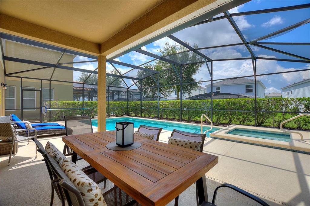 A covered patio features a wooden dining table, a swimming pool, and a screened enclosure — 5368 OAKBOURNE AVENUE, DAVENPORT, FL