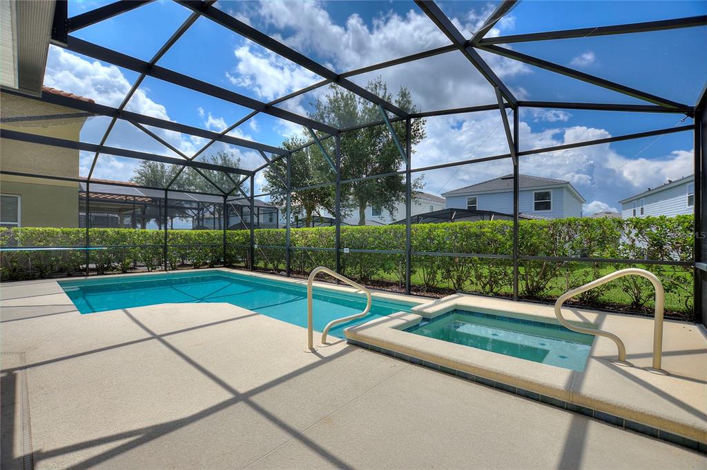 A screened-in patio features a swimming pool, a raised spa, and a manicured hedge — 5368 OAKBOURNE AVENUE, DAVENPORT, FL