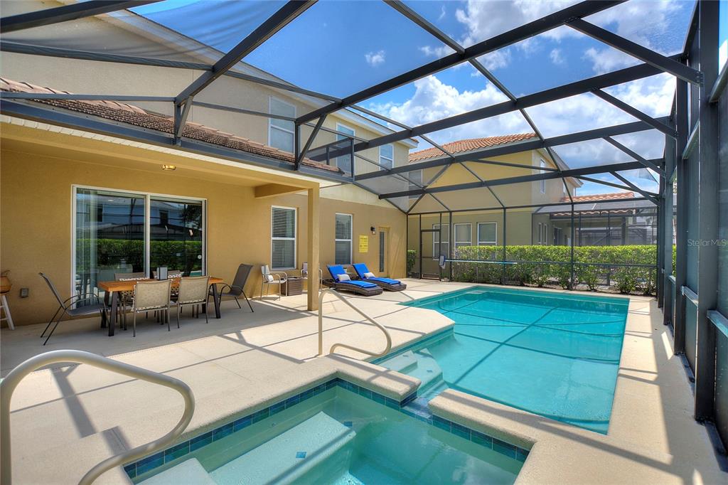 A screened-in patio features a swimming pool, a hot tub, and outdoor dining furniture — 5368 OAKBOURNE AVENUE, DAVENPORT, FL