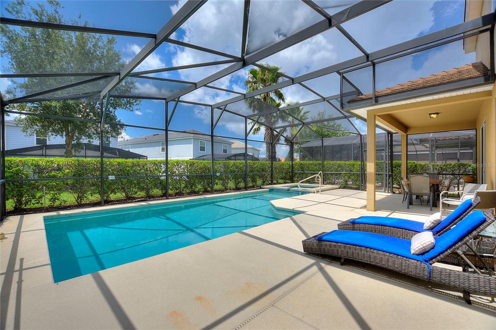 A screened-in patio features a rectangular swimming pool, a hot tub, and two lounge chairs — 5368 OAKBOURNE AVENUE, DAVENPORT, FL