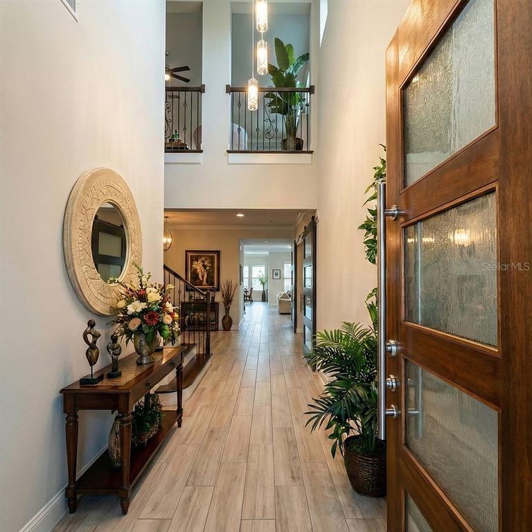 A bright entryway features wood-look tile floors, a wooden console table, and a tall front door — 3191 PLAYERS VIEW CIRCLE, LONGWOOD, FL