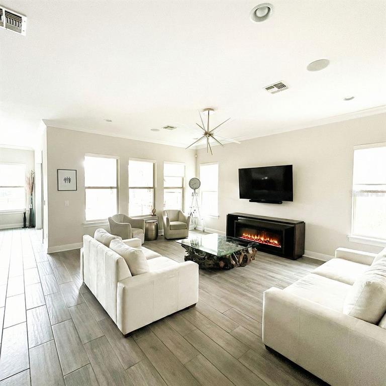 A bright living room features light tile floors, a fireplace, and neutral-toned furniture — 3191 PLAYERS VIEW CIRCLE, LONGWOOD, FL