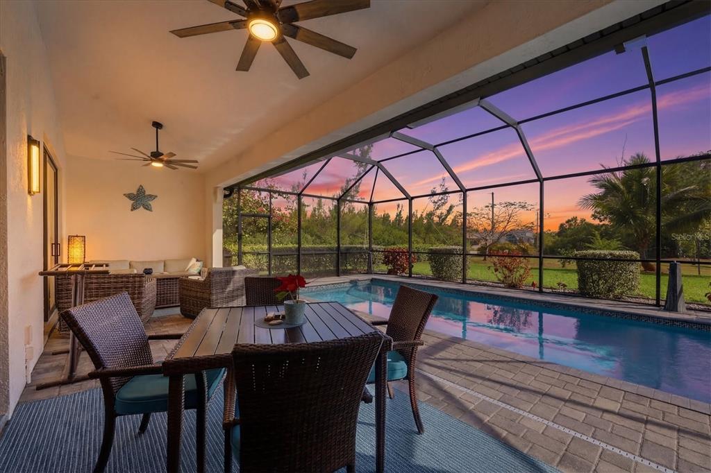 A covered patio features a dining set, lounge furniture, and a screened-in swimming pool — 10726 KEARSARGE CIRCLE, PORT CHARLOTTE, FL