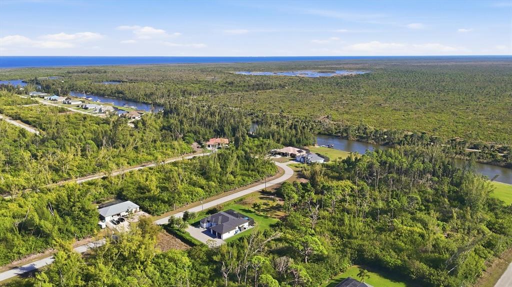 An aerial view shows several houses surrounded by dense vegetation and a winding canal — 10726 KEARSARGE CIRCLE, PORT CHARLOTTE, FL