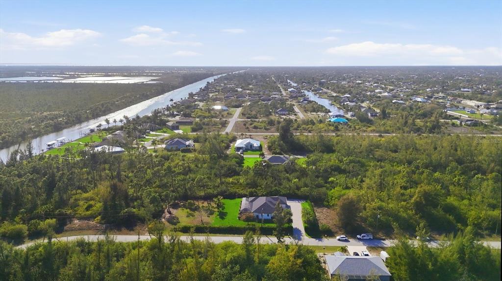 An aerial view shows houses scattered among dense vegetation and canals in a suburban area — 10726 KEARSARGE CIRCLE, PORT CHARLOTTE, FL