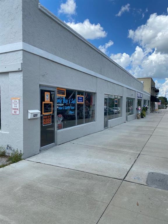 A gray commercial building with storefront windows and a sidewalk under a blue sky — 1219 W MAIN STREET, LEESBURG, FL