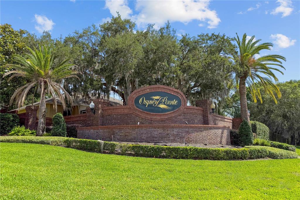 A brick entrance sign for Osprey Pointe sits in front of large trees and palms — Lot 47 OSPREY POINTE BOULEVARD, CLERMONT, FL