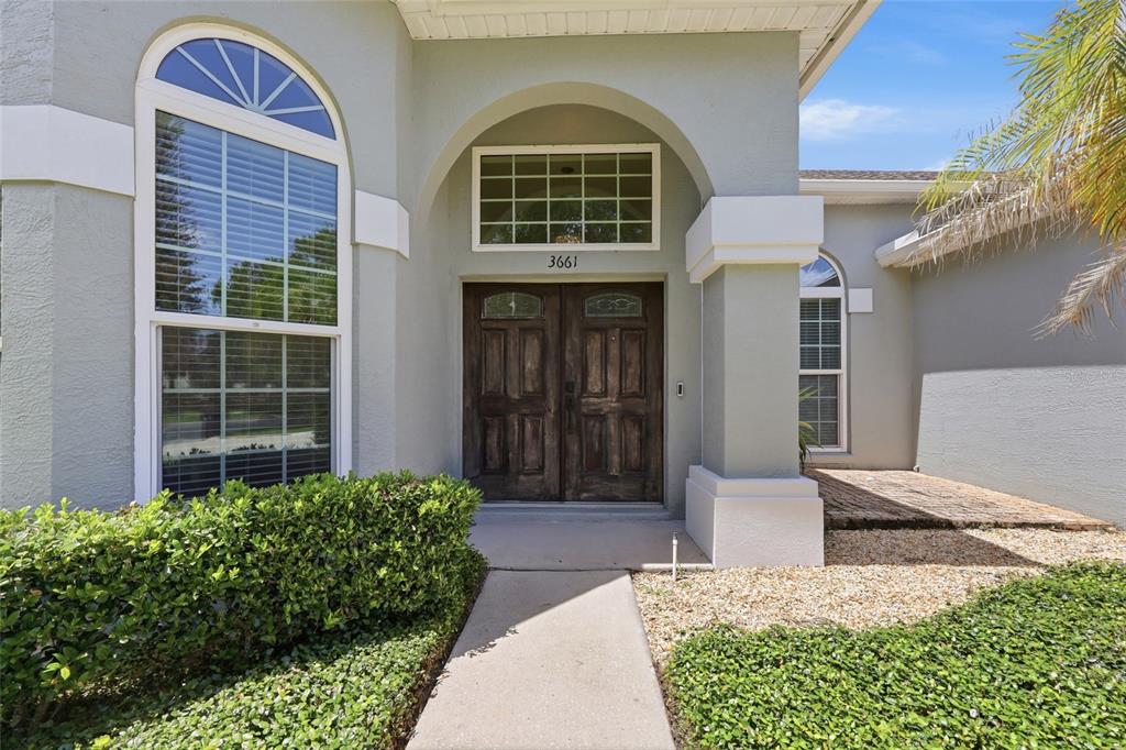 A concrete walkway leads to the double front doors of a light-colored stucco house — 3661 CRESCENT PARK BOULEVARD, ORLANDO, FL