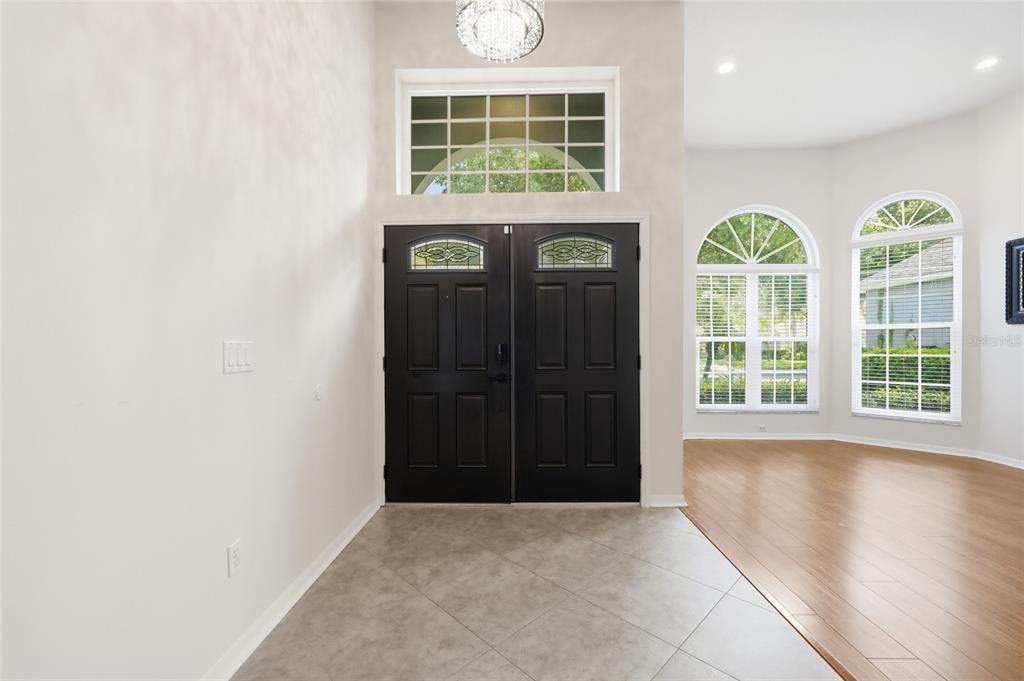 A foyer with a black double door, tile flooring, and a high ceiling with a chandelier — 3661 CRESCENT PARK BOULEVARD, ORLANDO, FL