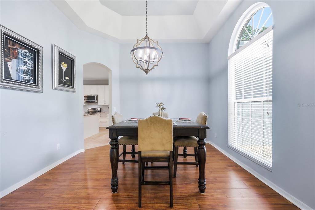A dining room with a tray ceiling, chandelier, wood flooring, and a large arched window — 3661 CRESCENT PARK BOULEVARD, ORLANDO, FL
