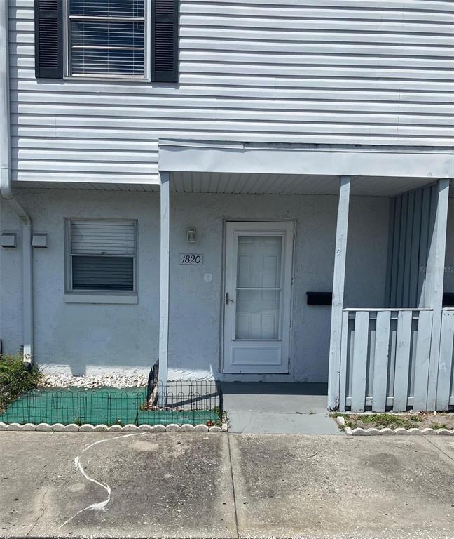 The exterior of a two-story townhouse features white siding, a front door, and a porch — 1820 AMBERLY AVENUE UNIT T10, ORLANDO, FL