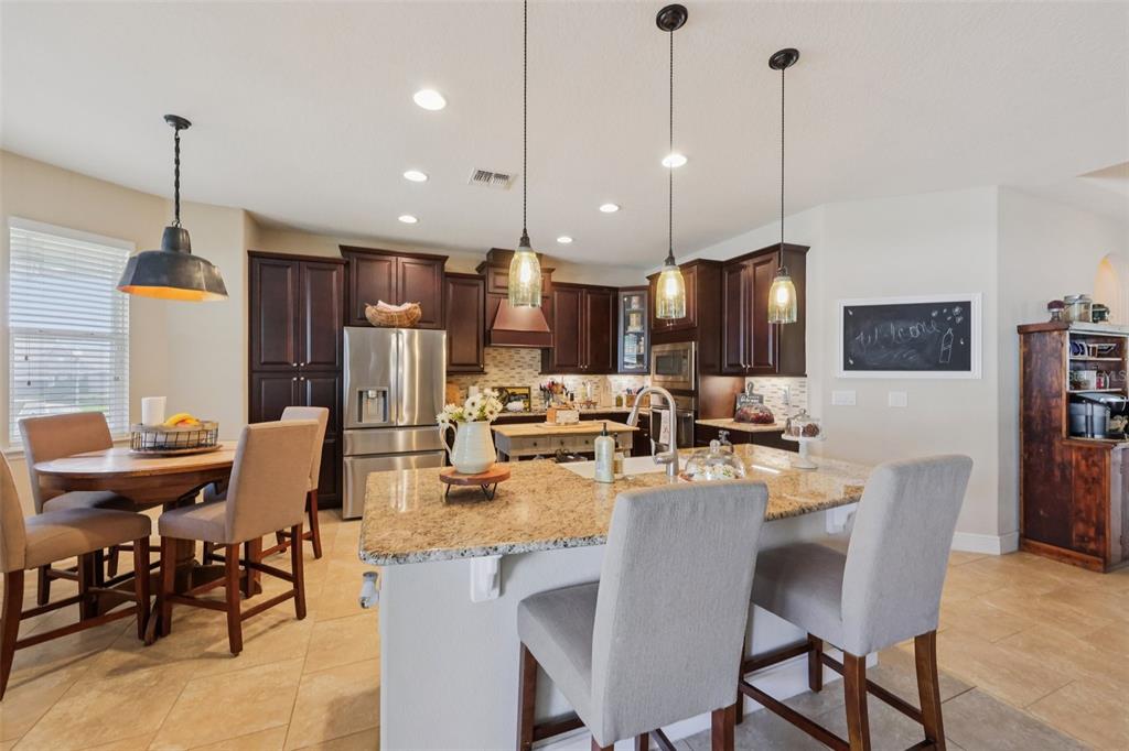 A kitchen features dark wood cabinets, granite countertops, a center island, and pendant lighting — 4001 CHANDLER ESTATES DRIVE, APOPKA, FL